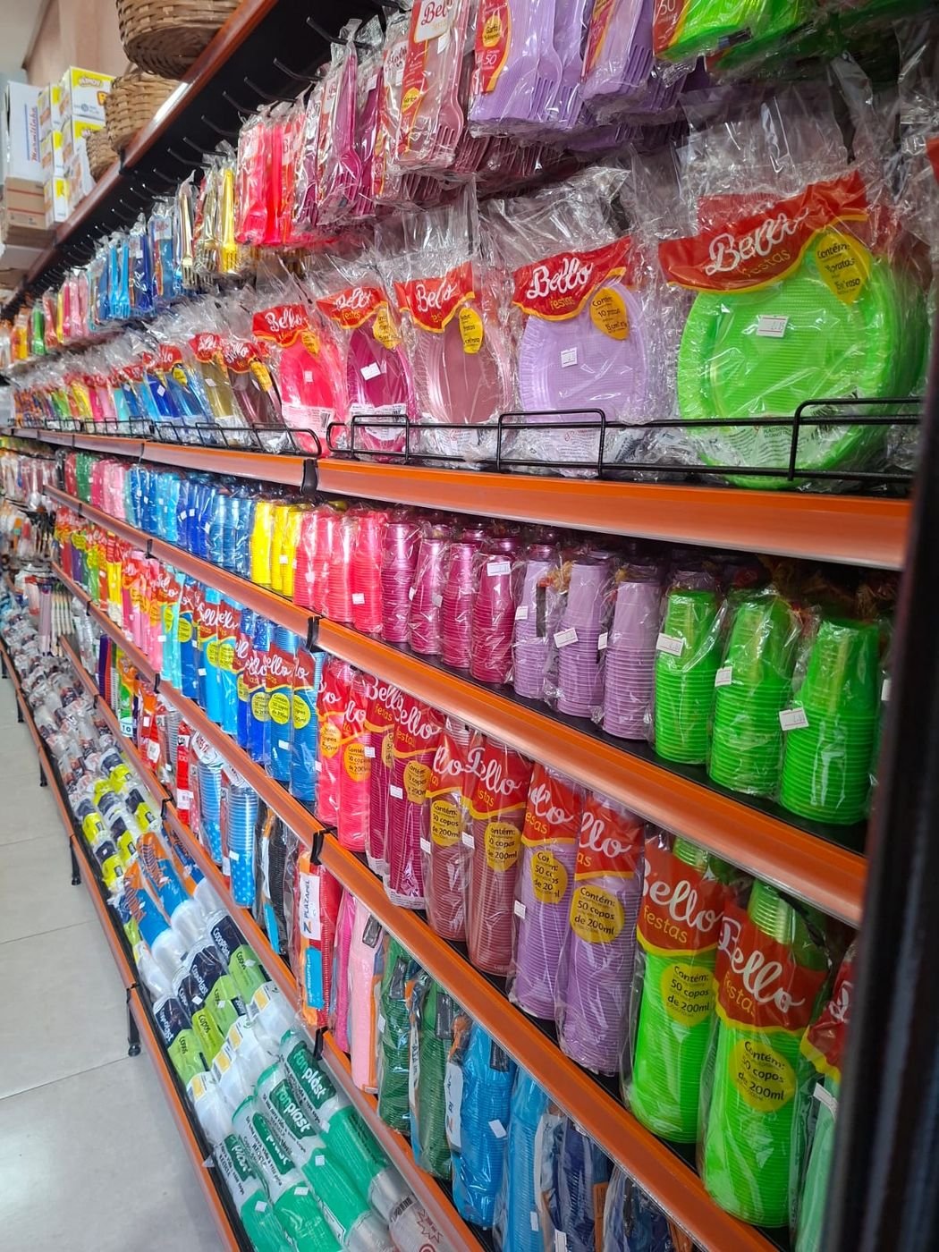 Corredor interno da Líder Festas com prateleiras de copos e pratos descartáveis coloridos