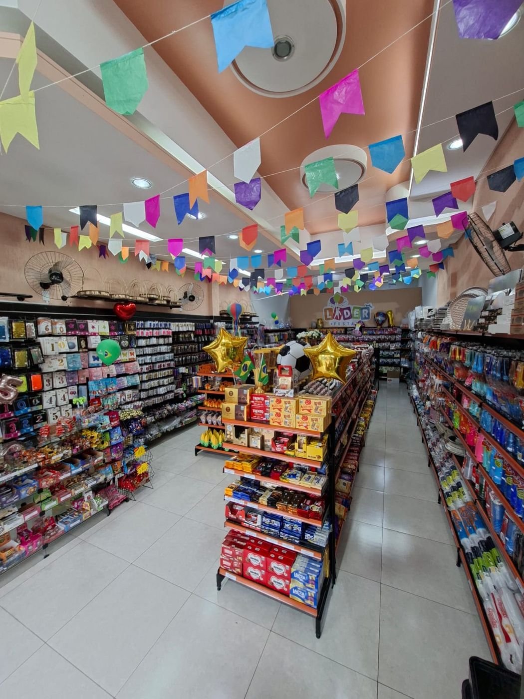 Balões dourados e chocolates variados expostos na Líder Festas